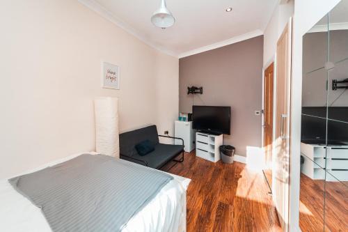 a bedroom with a bed and a flat screen tv at Private en-suite Room @ Liverpool street, Brick Ln in London