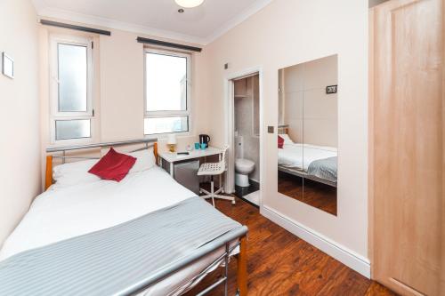 um quarto com uma cama e uma secretária com um espelho em Private en-suite Room @ Liverpool street, Brick Ln em Londres