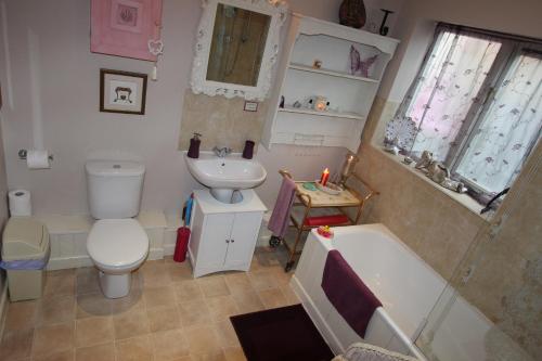 グラストンベリーにあるGlastonbury Rose Cottageのバスルーム(トイレ、洗面台、バスタブ付)