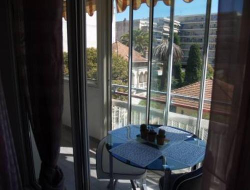 une table bleue assise devant une fenêtre dans l'établissement Appartement Les Palmiers, à Juan-les-Pins