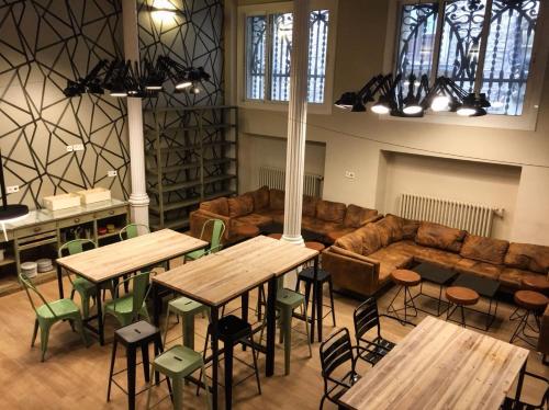 una grande stanza con tavoli in legno e un divano di Safestay Barcelona Gothic a Barcellona