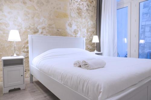 una camera da letto con un letto bianco con due asciugamani di Ausone Beautiful loft apartment in historical center + terrace and parking a Bordeaux
