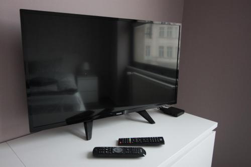 a flat screen tv sitting on a table with two remote controls at Downtown Apartments in Plzeň