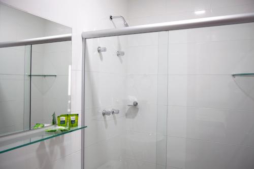 ein weißes Bad mit einer Dusche und einer Glastür in der Unterkunft Jabó Inn Hotel in Jaboticatubas