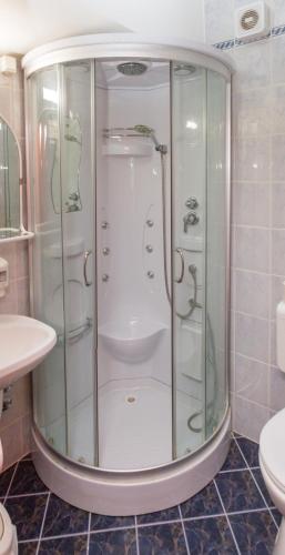 a shower with glass doors in a bathroom at Hotel Rudolf in Hajdúszoboszló