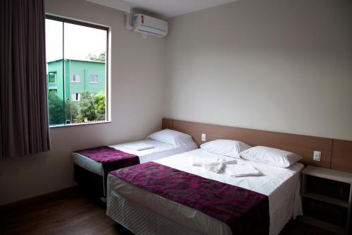 um quarto de hotel com duas camas e uma janela em Jabó Inn Hotel em Jaboticatubas