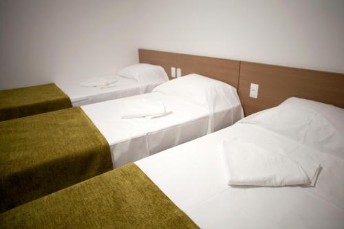 two beds in a hotel room with white sheets at Jabó Inn Hotel in Jaboticatubas