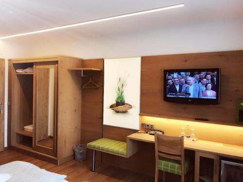 a living room with a television on a wall at Hotel am Wiesenhang - Garni in Bad Kohlgrub
