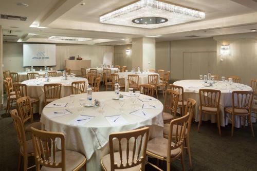 a room full of tables and chairs with white linens at Amalia Hotel Athens in Athens