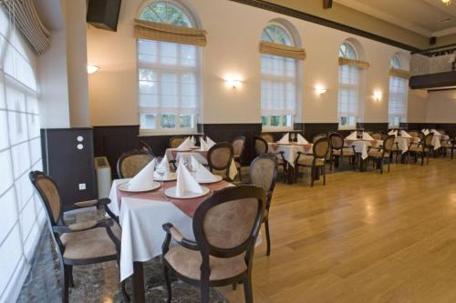 a dining room with tables and chairs and windows at Hotel Apollo in Darłówko