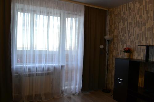 ノヴォシビルスクにあるАпартаменты на Немировича-Данченкоの白いカーテン付きの窓のある部屋