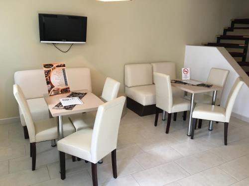 a waiting room with two tables and chairs and a tv at Mosoly Szallashely in Szeged