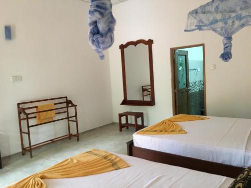 a room with two beds and a mirror at Sigiri Rangana Guesthouse in Sigiriya