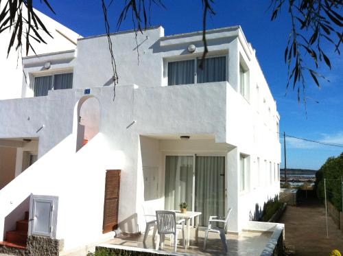 a white house with a table and chairs at Apartamentos Eugenio la Sabina in La Savina