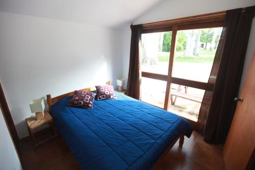 a bedroom with a blue bed with a large window at Estancia Termal San Nicanor in Termas de San Nicanor