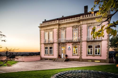 a pink mansion with a sunset in the background at Casa Altamira in Espadanedo