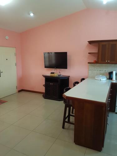 a kitchen with a table and a tv on the wall at Piarco Village Suites in Piarco