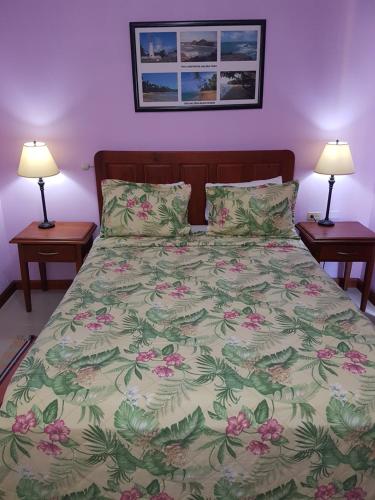 a bed in a bedroom with two lamps on tables at Piarco Village Suites in Piarco