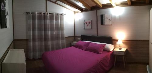 1 dormitorio con 1 cama con manta morada en Bungalows Cantia en Suances