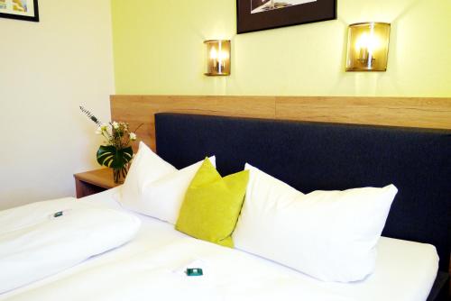 a bed with white pillows and a blue headboard with lights at Hotel Grader in Neustadt an der Waldnaab