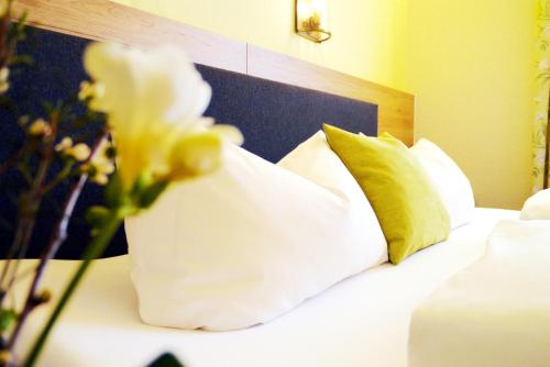a bedroom with a bed with white pillows and flowers at Hotel Grader in Neustadt an der Waldnaab