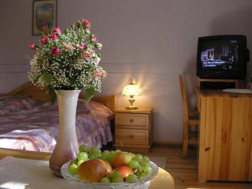 a vase with flowers and a bowl of fruit on a table at Villa Johanna Guesthouse in Pärnu