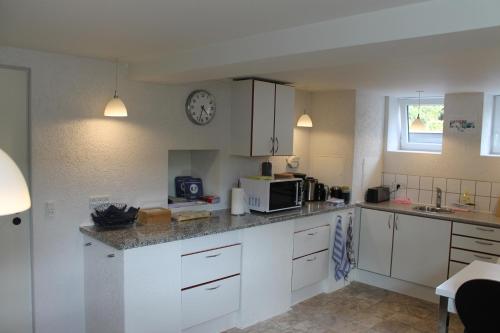 a kitchen with white cabinets and a clock on the wall at Amalie Bed and Breakfast & Apartments in Odense