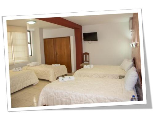 a hotel room with two beds and a mirror at Hotel Villa Rita Chiclayo in Chiclayo