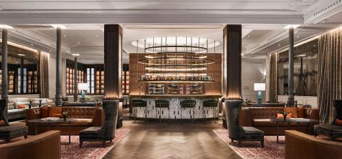 a lobby of a hotel with chairs and a chandelier at Gran Hotel Inglés - The Leading Hotels of the World in Madrid