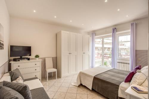 a bedroom with a bed and a tv and a couch at Rome4Guest Ostia in Lido di Ostia