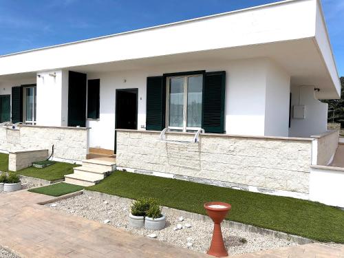 a white house with black windows and grass at Residence Pegaso in Nettuno