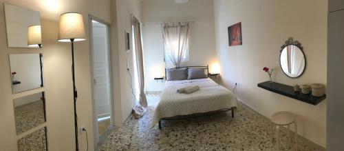 a white bedroom with a bed and a mirror at Sunshine's house near the beach, 10 min from the airport in Artemida