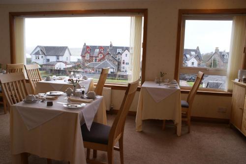 a dining room with two tables and two windows at Greencourt Guest House in Oban