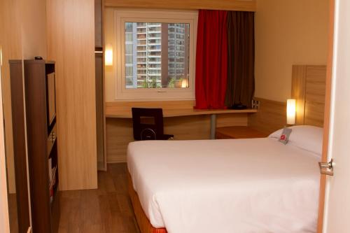 a bedroom with a bed and a desk and a window at ibis Santiago Las Condes in Santiago