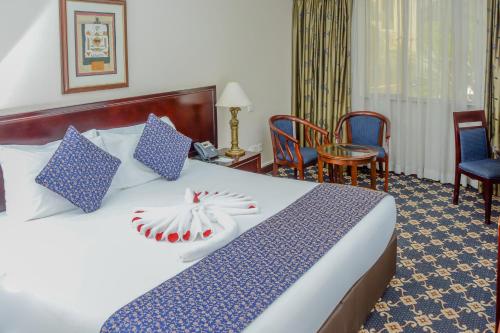 a hotel room with a bed with blue and white pillows at Jacaranda Hotel Nairobi in Nairobi