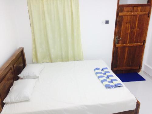 a bedroom with a bed with a blue and white pillow at Bindu Homestay in Wellawaya