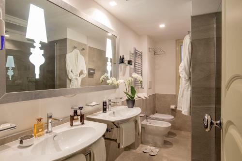 a bathroom with two sinks and a toilet and a mirror at Ludovisi Palace Hotel in Rome