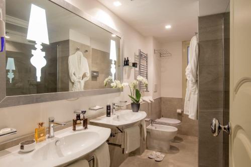 uma casa de banho com 2 lavatórios, um WC e um espelho. em Ludovisi Palace Hotel em Roma