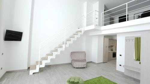 a white living room with stairs and a chair at Ecumano Space in Naples