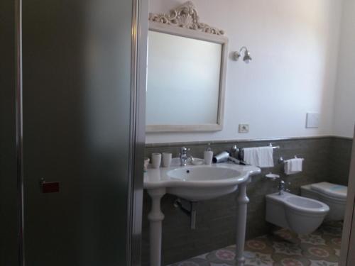 a bathroom with a sink and a toilet and a mirror at Agriturismo Salinola in Ostuni