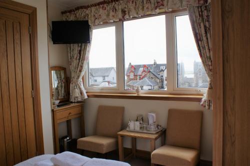 a room with a bed and two chairs and a window at Greencourt Guest House in Oban