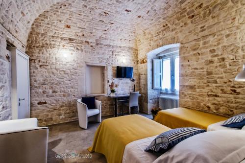 a bedroom with two beds and a brick wall at Borgo Noci in Noci