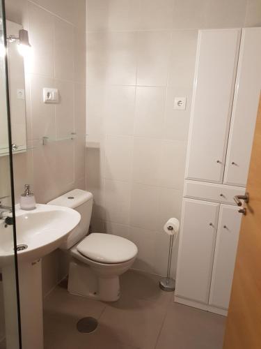 a white bathroom with a toilet and a sink at Las Terrazas De La Torre Apartment in Roldán