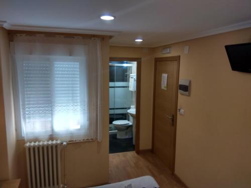 a bathroom with a toilet and a window with a radiator at Hostal Lido in Ourense