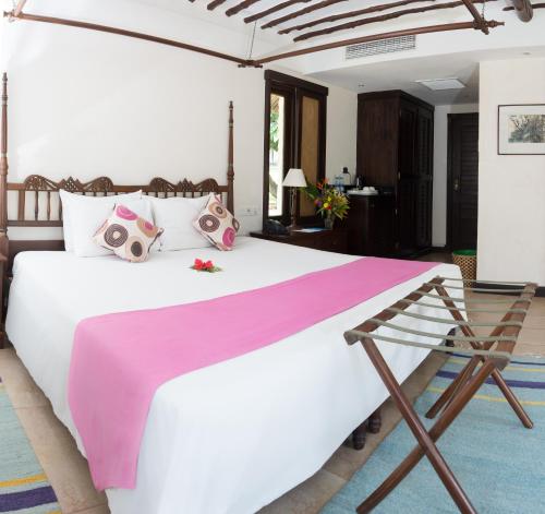 a bedroom with a large white bed with a pink blanket at Jacaranda Indian Ocean Beach Resort in Diani Beach