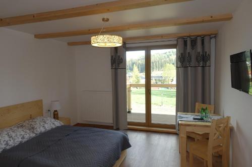 a bedroom with a bed and a desk and a window at Willa Zaolzie in Istebna