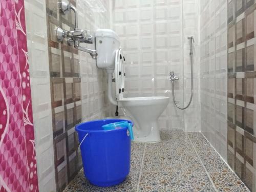 a bathroom with a toilet and a blue bucket at Andaman Vacations Home in Port Blair