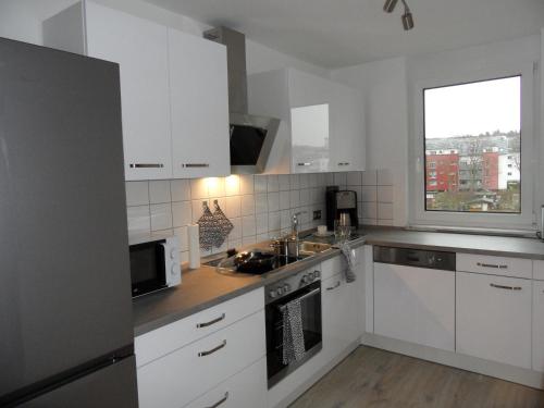 a white kitchen with white cabinets and a window at ViewMaLa - moderne Ferienwohnung mit Panorama in Bad Kreuznach
