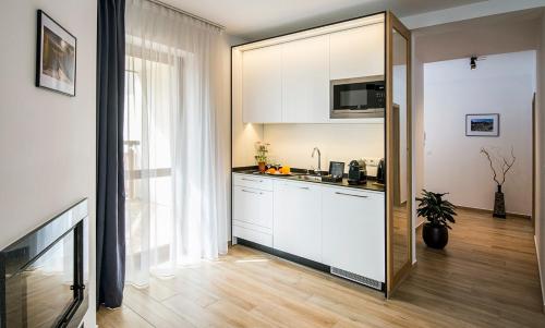 a kitchen with white cabinets and a large window at Apartamenty Forma Tatrica in Zakopane