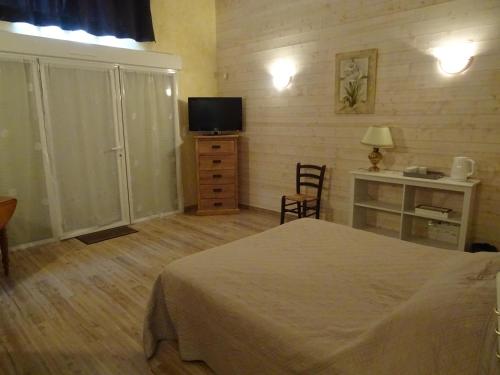 a bedroom with a bed and a dresser and a television at La Lauriére in Treize-Vents